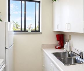 London apartment for rent - A kitchen with a white fridge, white cabinets, and a window.
