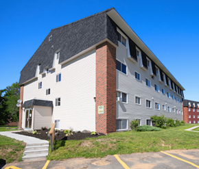 Fredericton apartment for rent - A white building with a grey roof and a brick chimney.