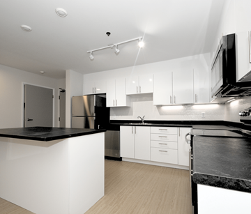 Halifax apartment for rent - A modern kitchen with white cabinets and black countertops.
