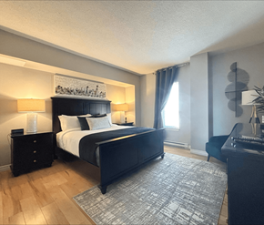 Moncton apartment for rent - A bedroom with a large bed and a painting above it.