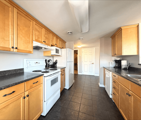Moncton apartment for rent - A kitchen with wooden cabinets and black countertops.