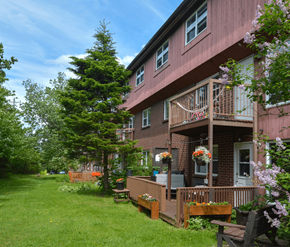 Halifax apartment for rent - A red building with a balcony and a green lawn in front.