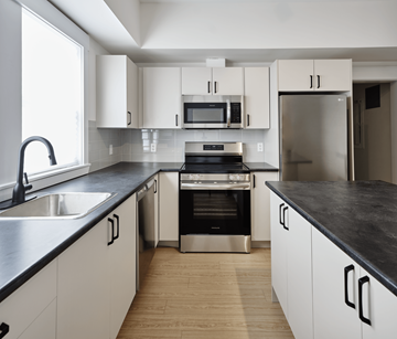 Halifax apartment for rent - A modern kitchen with white cabinets and black countertops.