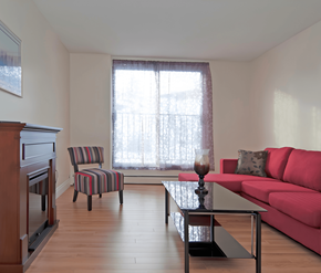 Halifax apartment for rent - A living room with a red couch, a striped chair, and a wooden floor.