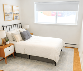 Ottawa apartment for rent - A bedroom with a white bed and a grey rug.