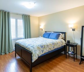 Moncton apartment for rent - A bedroom with a bed, nightstand, and window.