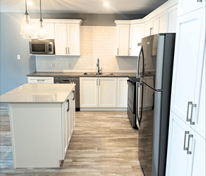 Fredericton apartment for rent - A kitchen with a black refrigerator and white cabinets.