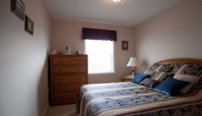 Stratford apartment for rent - A bedroom with a bed, nightstand, and window.