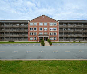Halifax apartment for rent - A red brick building with a parking lot in front.