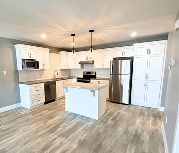 Fredericton apartment for rent - A kitchen with white cabinets and a wooden floor.