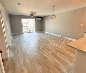 Fredericton apartment for rent - A room with wooden flooring and a large window.