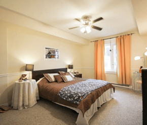 Fredericton apartment for rent - A bedroom with a large bed and a ceiling fan.