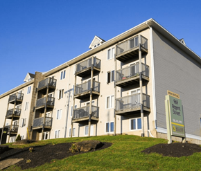 Fredericton apartment for rent - A multi-story apartment building with a sign that reads "Sale" in front of it.