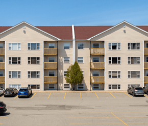 Saint John apartment for rent - A parking lot in front of a tan apartment building with cars parked.