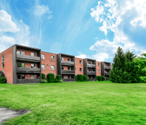London apartment for rent - A row of red brick apartment buildings with green grass in front.