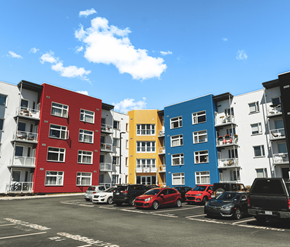 St. Johns apartment for rent - A row of colorful apartment buildings with cars parked in front.