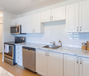 Saint John apartment for rent - A kitchen with white cabinets and a marble countertop.