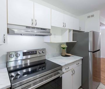 Moncton apartment for rent - A modern kitchen with a stainless steel oven and white cabinets.