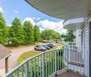 Moncton apartment for rent - A view from a balcony overlooking a parking lot and trees.