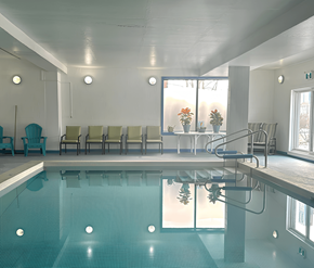 Moncton apartment for rent - A large indoor swimming pool with a row of chairs and a staircase.