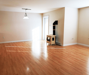 Fredericton apartment for rent - A room with wooden flooring and a wood-burning stove.
