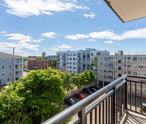 Moncton apartment for rent - A balcony overlooks a parking lot and buildings.
