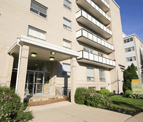 Moncton apartment for rent - A large apartment building with a green lawn in front.