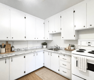 Moncton apartment for rent - A kitchen with white cabinets and a white stove top oven.