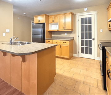 Dieppe apartment for rent - A kitchen with wooden cabinets and a black refrigerator.