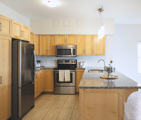 St. Johns apartment for rent - A kitchen with wooden cabinets and a black refrigerator.