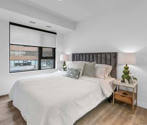 Kitchener apartment for rent - A bedroom with a large bed and a window with blinds.