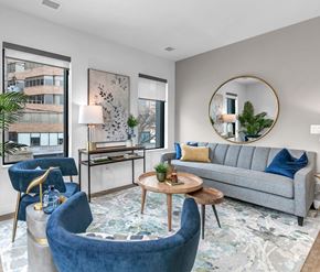 Kitchener apartment for rent - A living room with a grey couch, blue armchair, and a round mirror.
