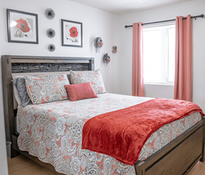 Moncton apartment for rent - A bed with a red blanket and a grey and red patterned duvet cover.