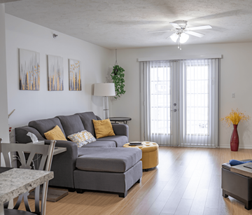 Moncton apartment for rent - A living room with a grey couch and a yellow ottoman.
