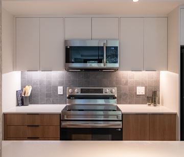 Halifax townhouse for rent - A modern kitchen with a stainless steel oven and microwave above a counter with a tiled backsplash.