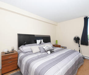Fredericton apartment for rent - A bedroom with a bed, nightstand, and lamp.