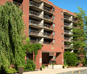 Fredericton apartment for rent - A red brick building with balconies and a parking sign.