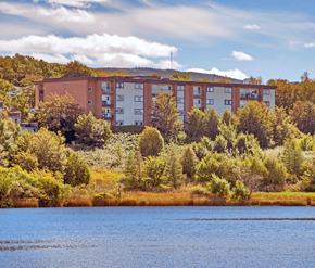 St. Johns apartment for rent - A large building with a red brick exterior is surrounded by trees and bushes.