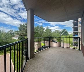 Dieppe apartment for rent - A balcony with a black railing overlooks a green lawn and trees.