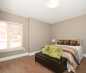 Dieppe apartment for rent - A bedroom with a bed, a bench, and a window.