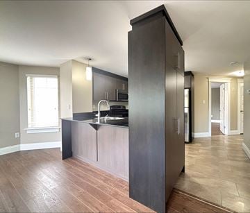 Dieppe apartment for rent - A kitchen with dark wood cabinets and a black countertop.