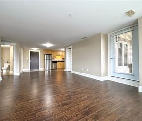 Dieppe apartment for rent - A spacious room with wooden floors and a large window with blinds.