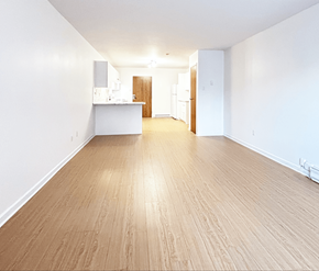Moncton apartment for rent - A spacious room with wooden flooring and white walls.