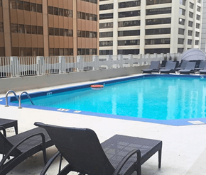 Calgary apartment for rent - A pool with chairs around it and buildings in the background.