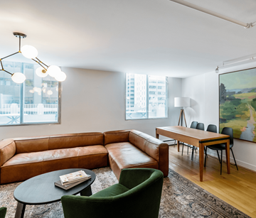 Calgary apartment for rent - A living room with a brown leather couch, green armchair, and a painting on the wall.
