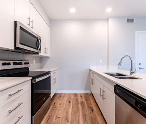 Edmonton apartment for rent - A kitchen with white cabinets and black appliances.