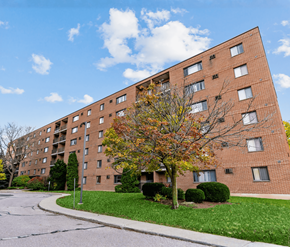 Kitchener apartment for rent - A tall brick apartment building with a tree in front of it.