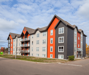 Moncton apartment for rent - A large apartment building with grey and orange accents.