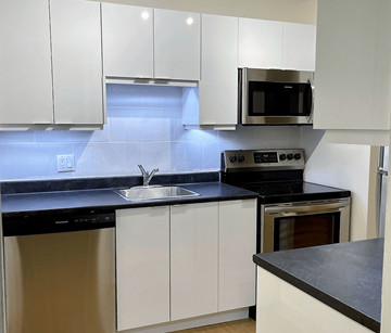 Bedford apartment for rent - A modern kitchen with white cabinets and black countertops.