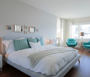 Dieppe apartment for rent - A bedroom with a large bed and a blue chair.